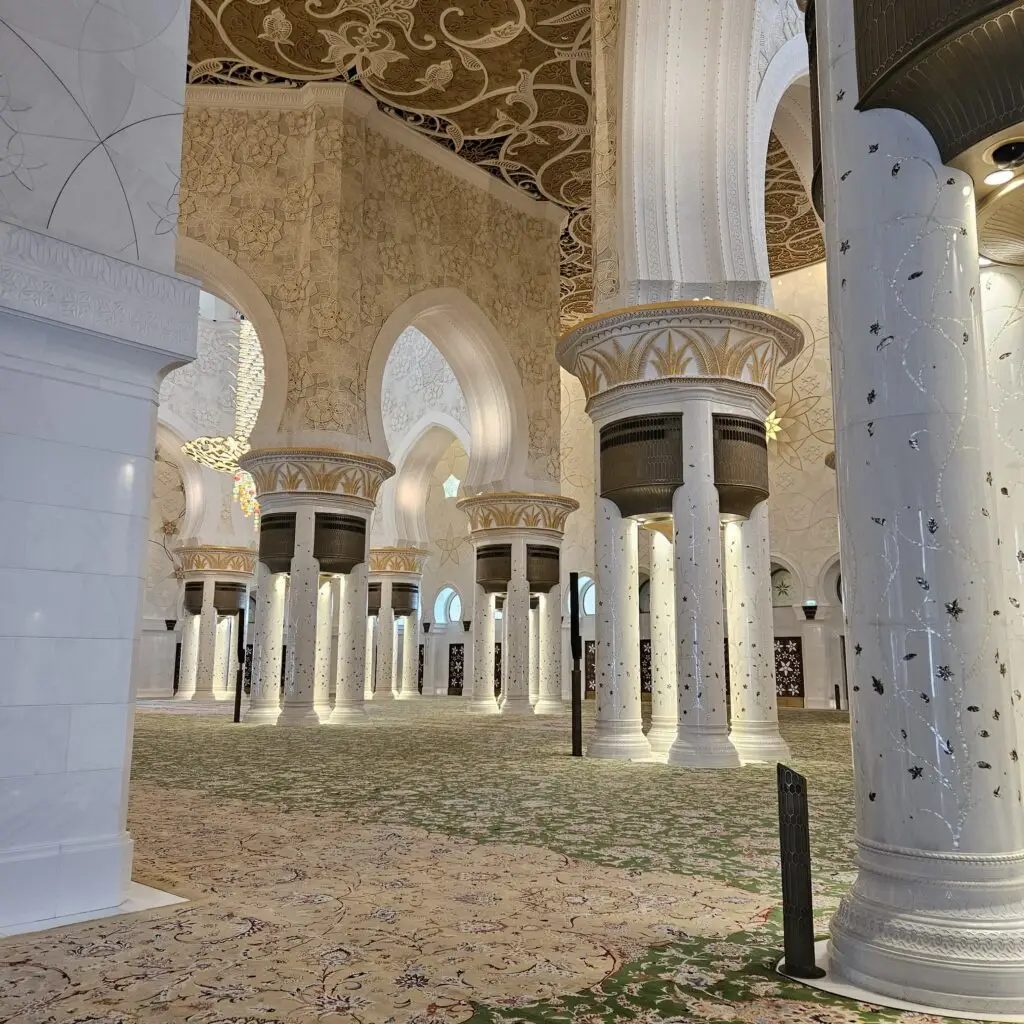 Exquisite white pillars and arches inside a grand mosque, showcasing Islamic architecture.